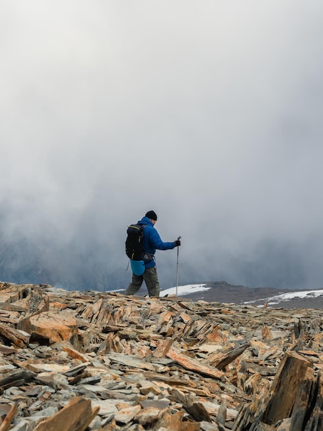 Solo klimmen Activiteiten man klim naar de top van een mistige stenen heuvel Mensen in moeilijke omstandigheden Moeilijke klim naar de top van de berg Verticale weergave