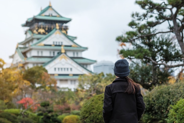 秋の大阪城を旅する一人の女性観光客、日本の大阪市を訪れるアジア人旅行者。休暇、目的地、旅行のコンセプト