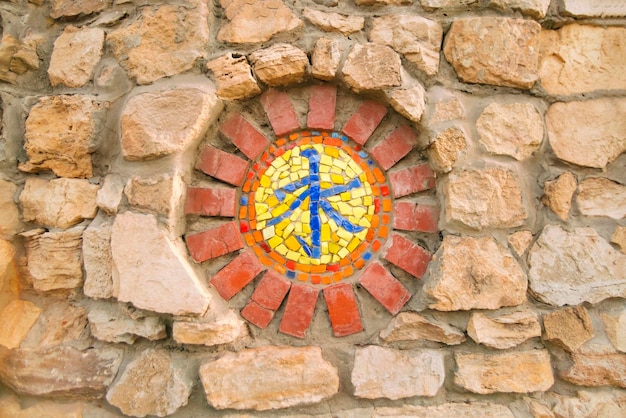 Solorfull circular mosaic with a religious symbol on the stone wall