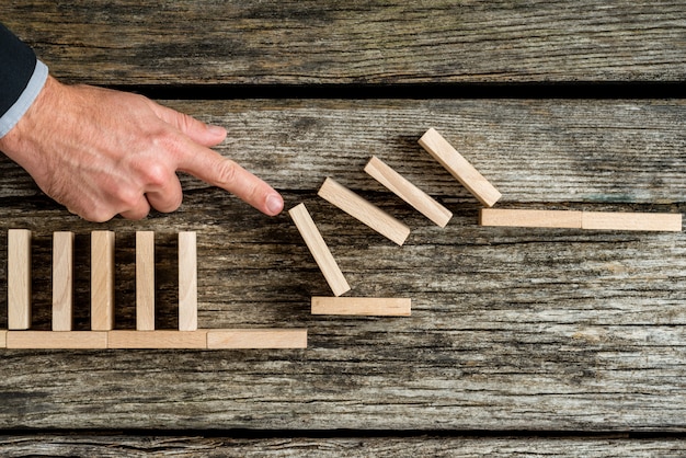 Solution concept with business man demonstrating stopping the domino effect