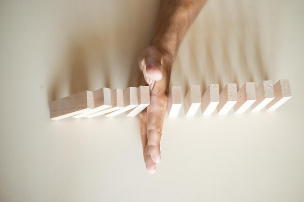 Foto concetto di soluzione con blocchi di legno fermati a mano dal cadere nella linea di domino