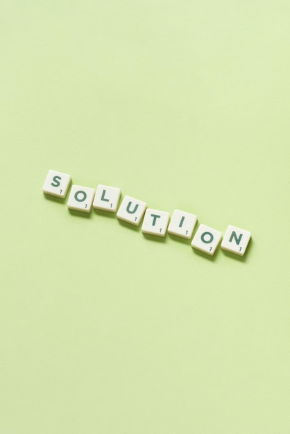 Solution formed of scrabble tiles on green background