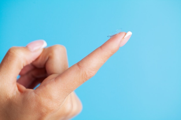 Photo solving vision problems, close up of woman holding contact lens