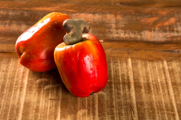 Some cashew fruit over a wooden surface.