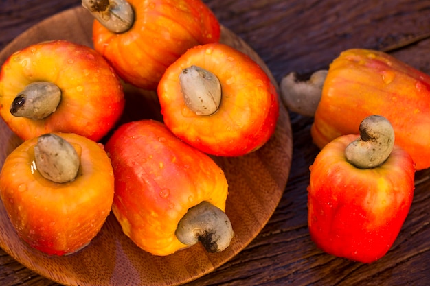 Some cashew fruit over a wooden surface.