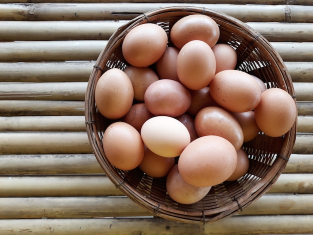 Some chicken eggs in the basket on the bamboo table