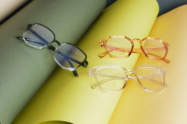 Foto alcuni occhiali diversi su carta arrotolata, sfondo geometrico, colori verdi, sfondo grigio, concetto di test della vista, bellissimi accessori moda alla moda nel negozio di ottica