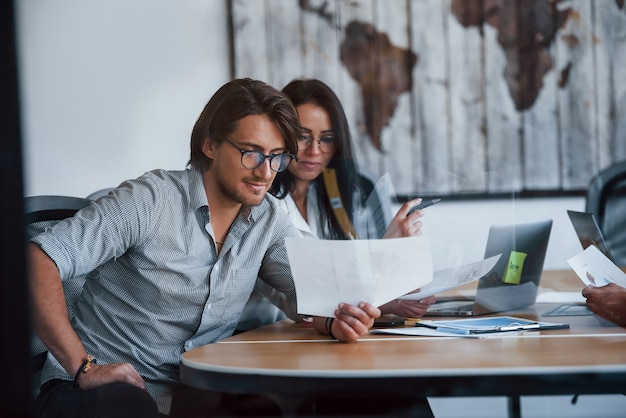 Some documents on the table and in hands. Young business people in formal clothes working in the office.