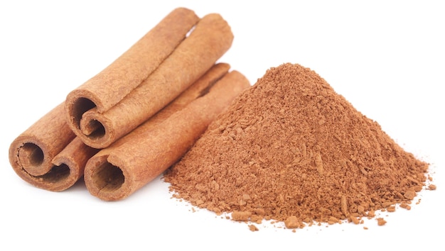 Some fresh aromatic cinnamon with powder spice over white background