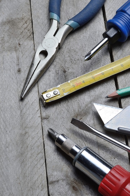 Alcuni strumenti di riparazione domestica giacciono su uno sfondo di legno. avvicinamento.