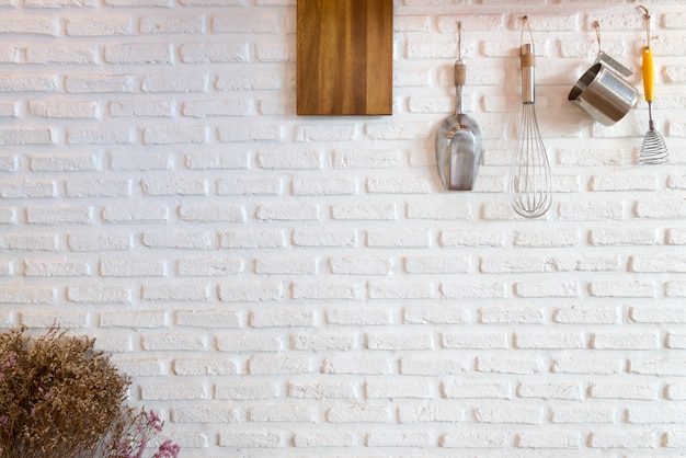 Some kitchenware hang on white brick wall 