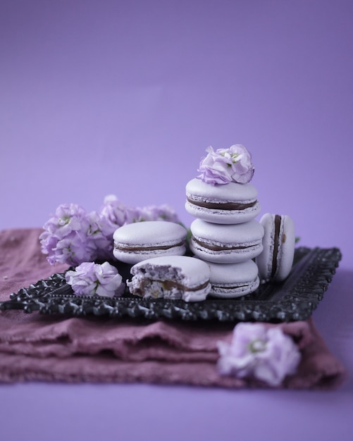 some lavender macarons on a lilac background, decorated with flowers. French pastries