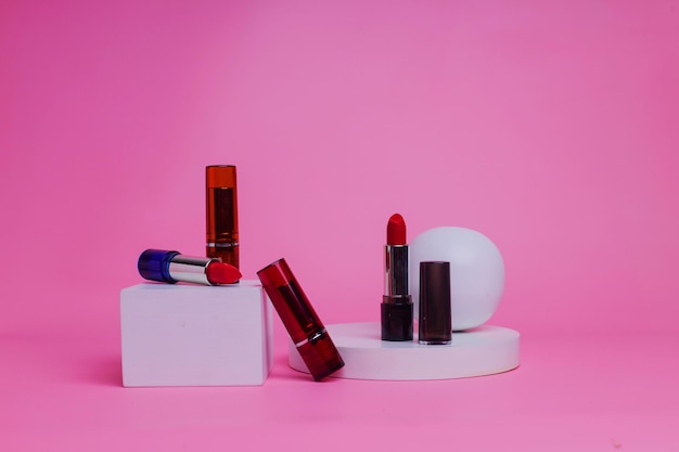 Photo some lipsticks are on the podium on a pink background.