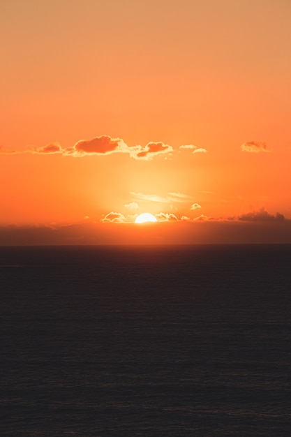 写真 コピースペースのある巨大な太陽とカラフルな夕日の間に地平線上のいくつかの巨大な雲