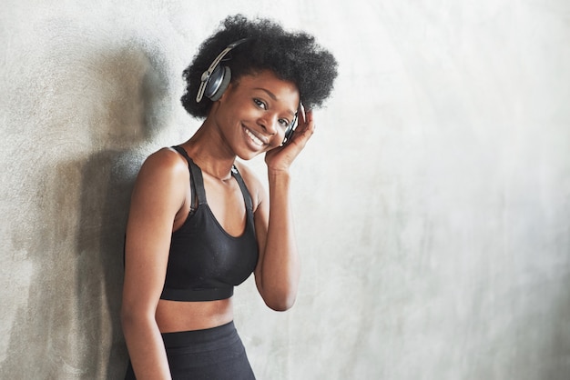 Some nice music there. Portrait of african american girl in fitness clothes having a break after workout