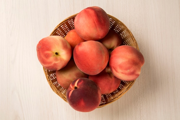 Some peaches in a basket over a wooden surface. Fresh fruits