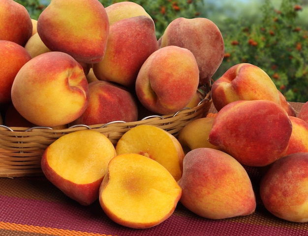 木の表面の上のバスケットのいくつかの桃。新鮮な果物