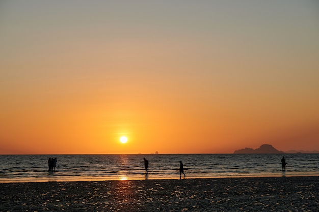 Some people are on a beach during sunset