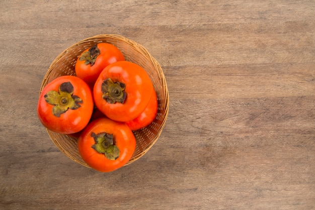 Some persimmon fruits over a wooden surface. Fresh fruits.