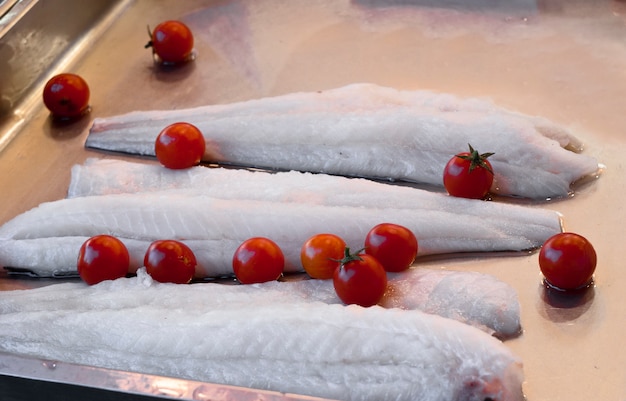 Photo some pieces of raw cod and tomatoes