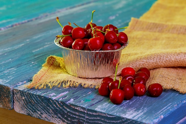 Some ripe cherries with sparkling water drops in small basket on a old wooden blue table