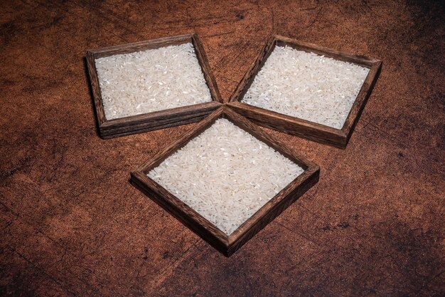 Some square containers of white rice in the dark background