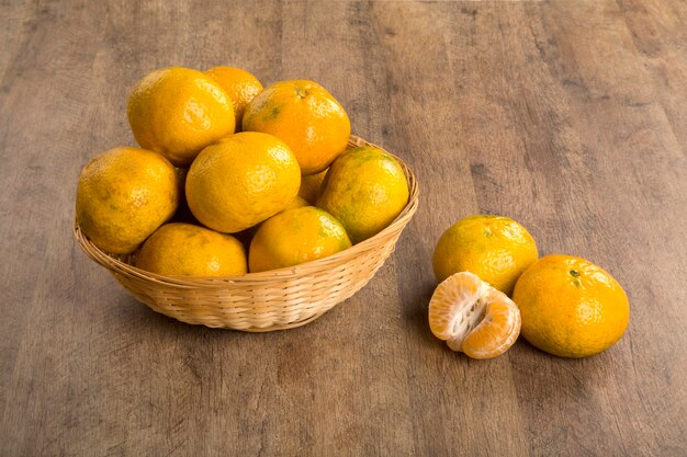 Some tangerines in a basket over a wooden surface. Fresh fruits.