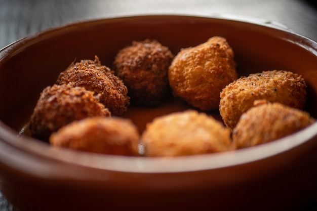 Some vegetarian croquettes in a clay pan on a dark table