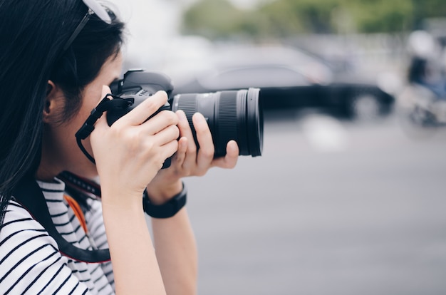 Some women hold Dslr camera on hand and take a photo in city 