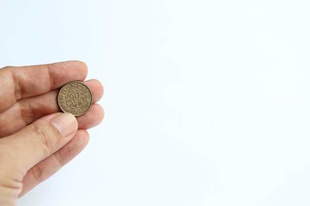 50セントルピアのインドネシアの1952年の古いコインを持っている誰かの指