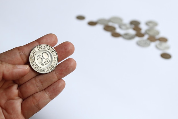 누군가가 배경에 흐릿한 동전이 있는 50센트 루피아의 1958년 인도네시아 오래된 동전을 들고 있습니다.