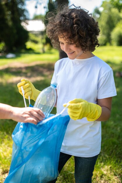 Someone helping a curly-haired teen to gather garbage