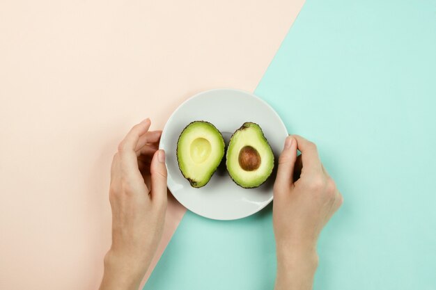 Someone is holding a plate of cut avocado