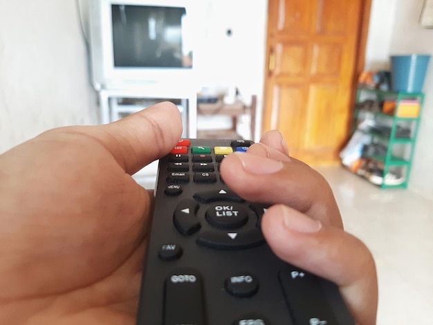 Photo someone is holding the remote control to turn off the tv