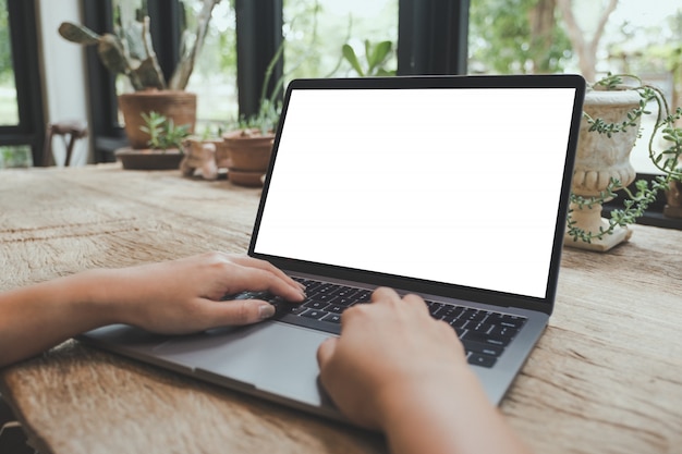 Someone is typing on a laptop with blank white desktop screen