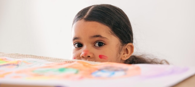 Someone made a mess and it wasnt me Shot of an adorable little girl peeking over a table while busy doing art