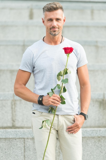 For someone special. Man with rose. Handsome man holding red rose. Attractive man with flower. Sexy man preparing natural gift for valentines day or birthday celebration.