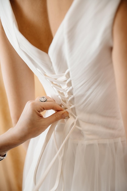 Someone tying the lace on the bride's corset