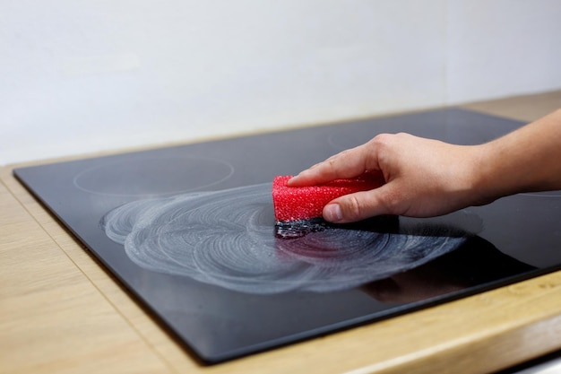 someone washes a ceramic electric stove with a sponge