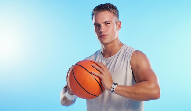 Something of a baller Studio portrait of a handsome young male basketball player posing with a ball against a blue background