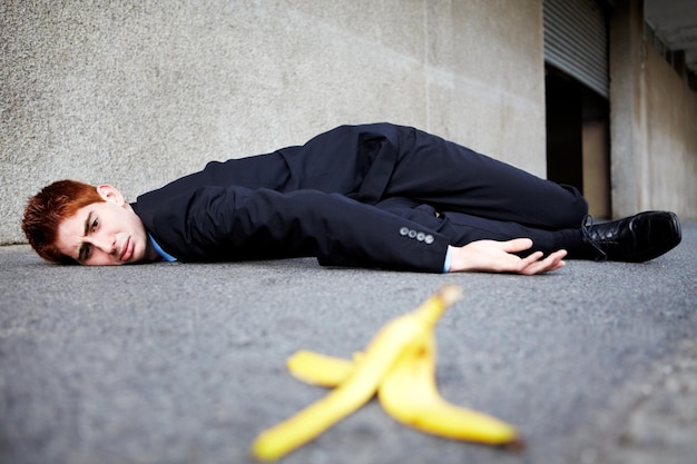 バナナの皮が避けられないこともあるバナナの皮をすべった後、地面に横たわっている若い男