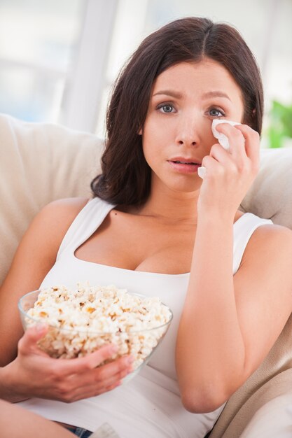 Sometimes I am so sentimental. Beautiful young woman holding handkerchief and crying while watching movie