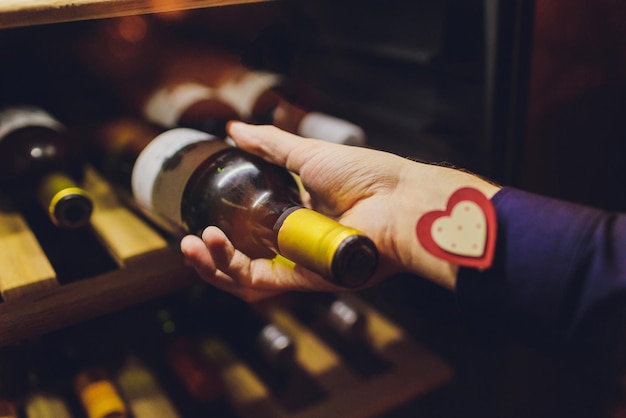 Sommelier met een wijnfles bij een rek in de winkel