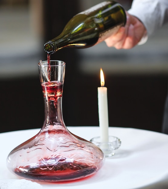 A sommelier pouring red wine into decanter