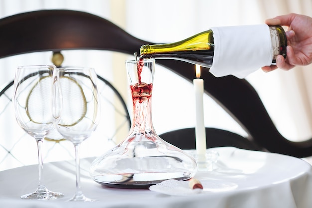 A sommelier pouring red wine into decanter