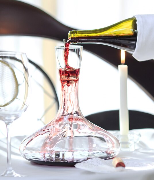 A sommelier pouring red wine into decanter