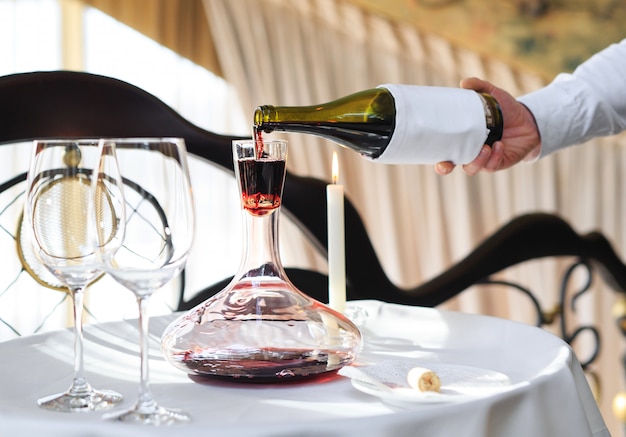 A sommelier pouring red wine into decanter