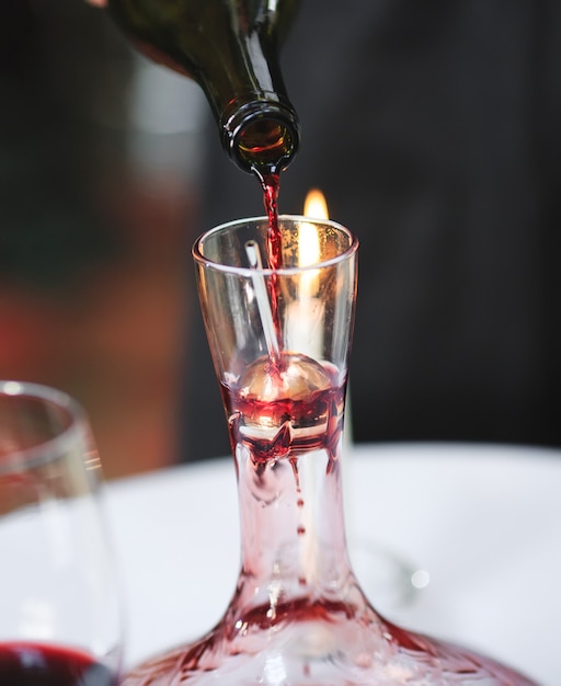 Foto un sommelier che versa il vino rosso nel decanter