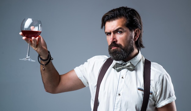 Sommelier tasting alcohol bartender stylish male barman\
drinking wine glass bearded man in suspenders drink red wine\
elegant businessman wear bow tie for formal event
