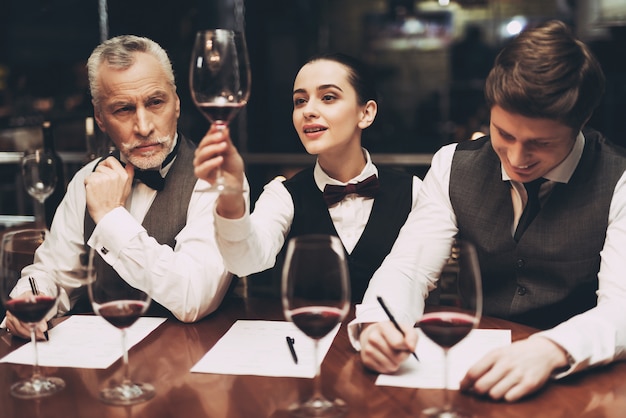 Sommeliers is Two Men and Woman in Restaurant.